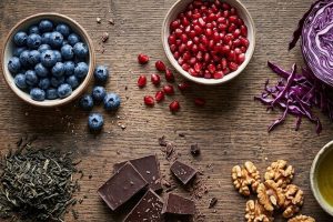 Продукты, богатые полифенолами: ягоды, гранат, зелёный чай и оливковое масло на деревянном столе